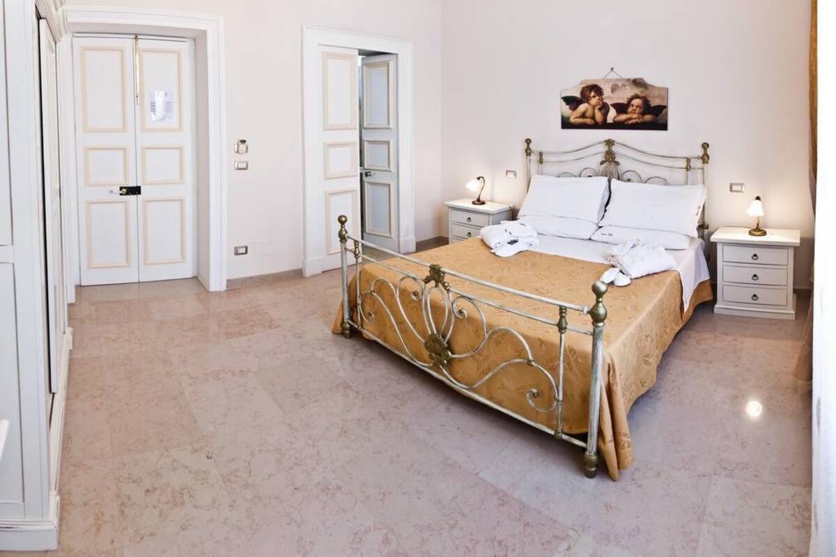 Une chambre à coucher avec un lit en métal, une table de chevet avec une lampe et un tableau accroché au mur.