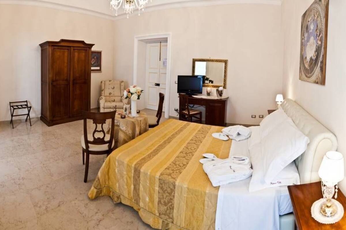 Une chambre d’hôtel comprenant un lit, un bureau, une chaise, une télévision et une armoire.