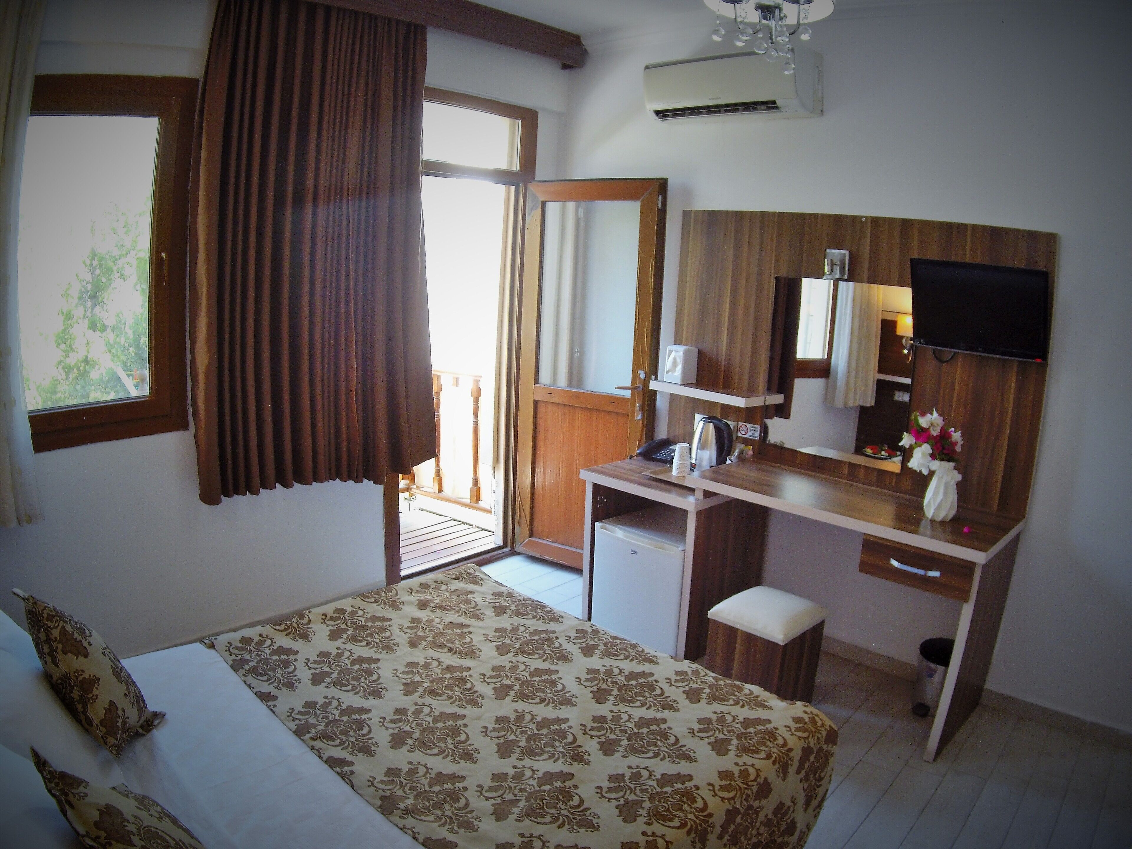 A hotel room with a bed, a desk, a chair, a television, and a window with curtains.