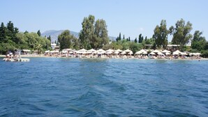 A beachside resort with multiple white umbrellas and lounge chairs along the shoreline. - Manuela Hotel (Bodrum)