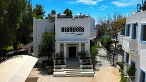 A hotel named "Manuela" with a modern architectural style, featuring a central entrance, outdoor seating area, and a staircase leading to the entrance. - Manuela Hotel (Bodrum)