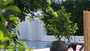 A pool area with steps leading to the water, surrounded by greenery and a white wall. - Manuela Hotel (Bodrum)