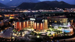Un hotel con patio central, varias construcciones y montañas al fondo.