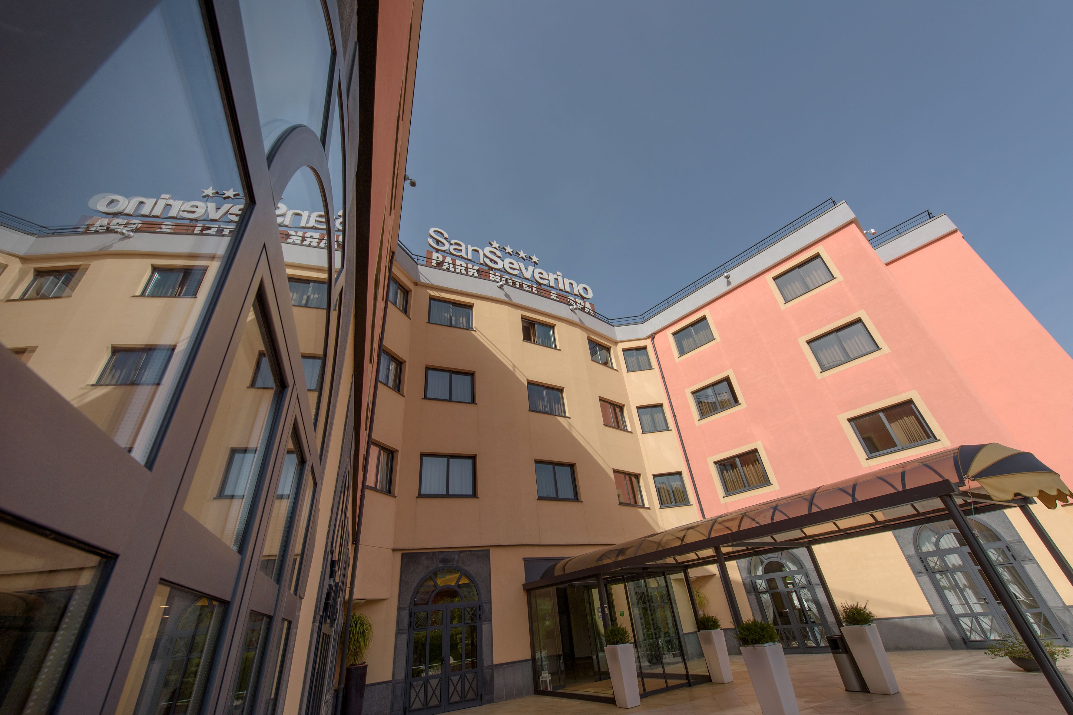 A hotel with a modern design, featuring a prominent sign for 'SanSeverino' and a covered entrance area.