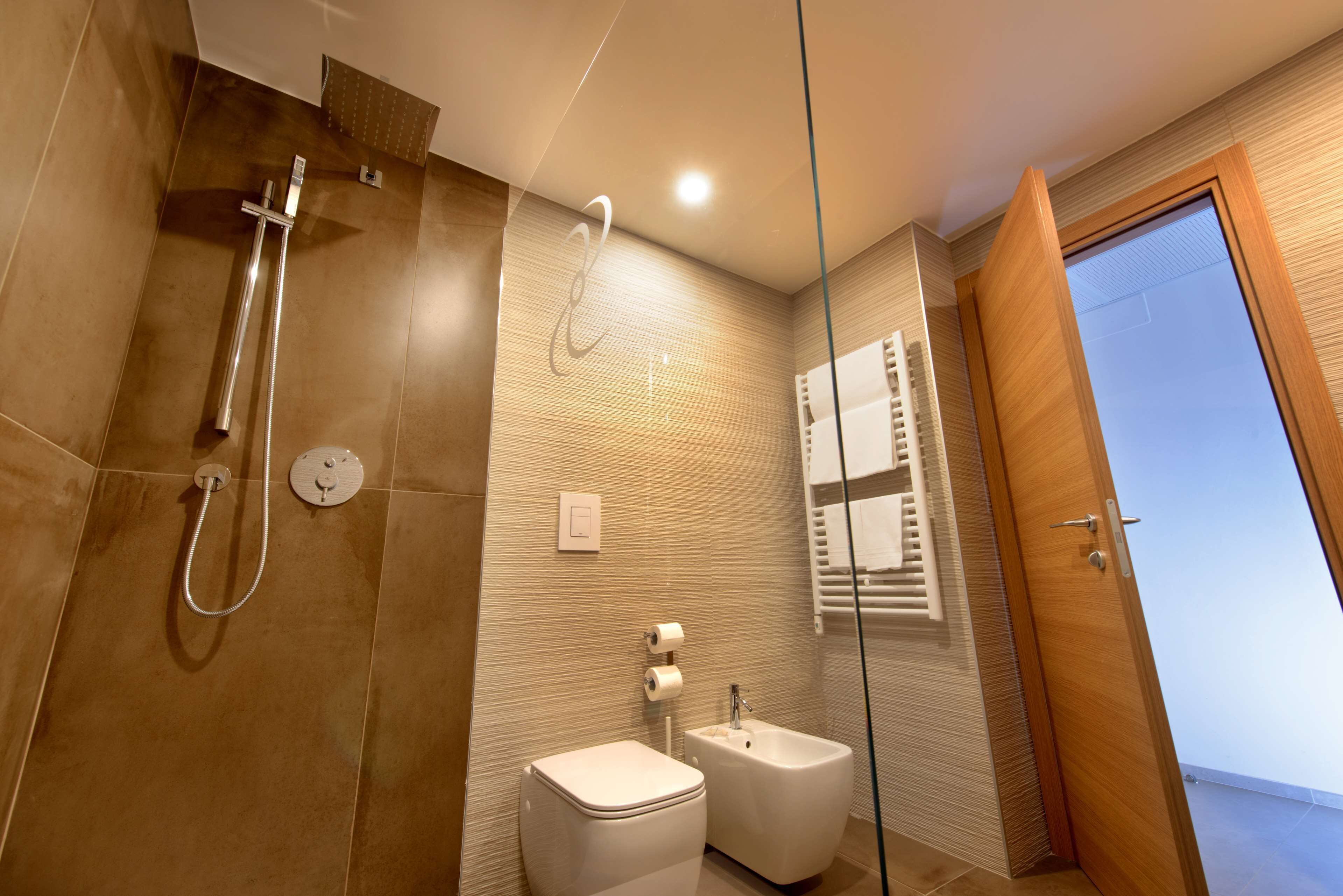 A modern bathroom with a glass shower enclosure, a bidet, and a toilet.