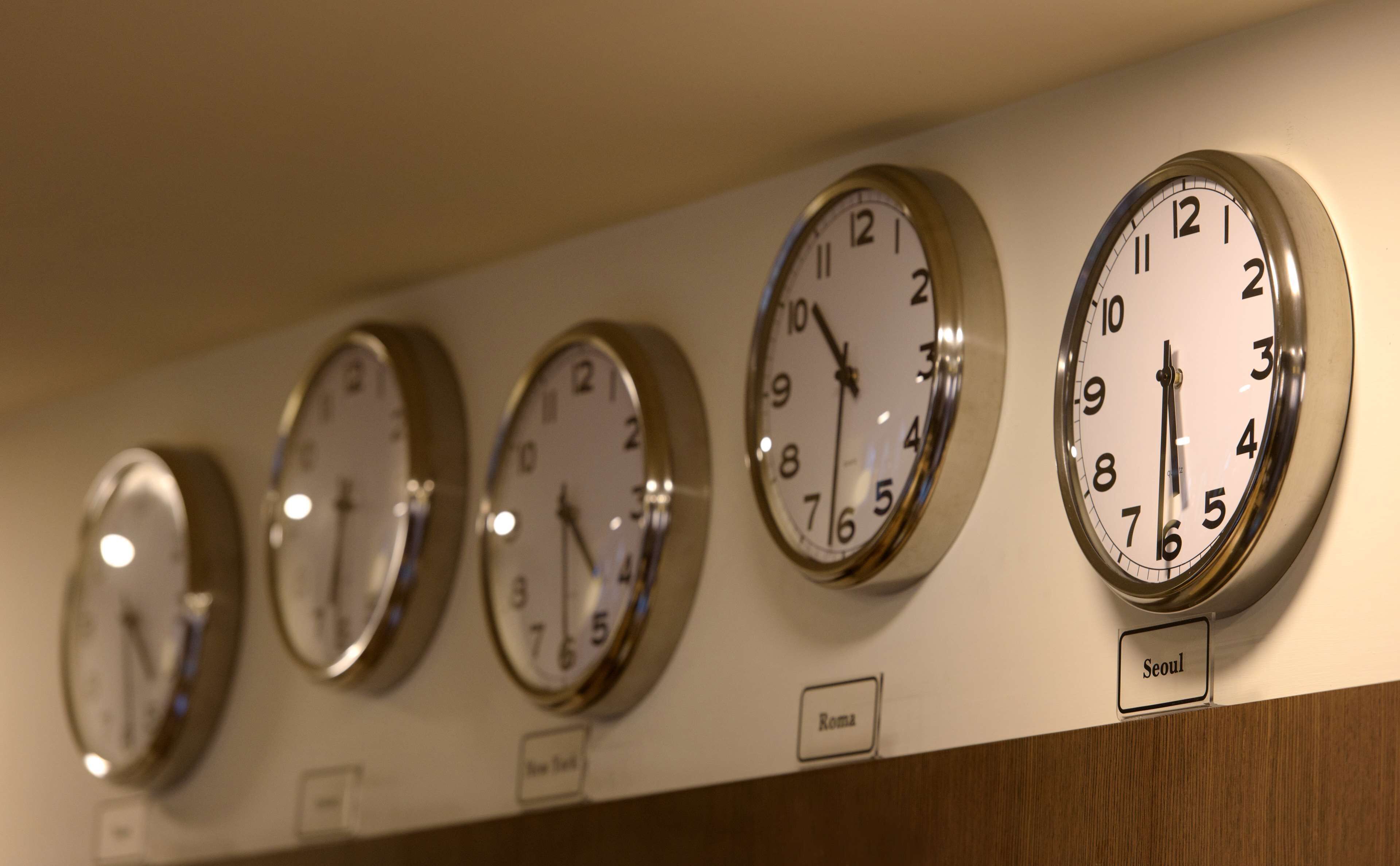 A row of wall clocks with Roman numerals, each labeled with a city name.