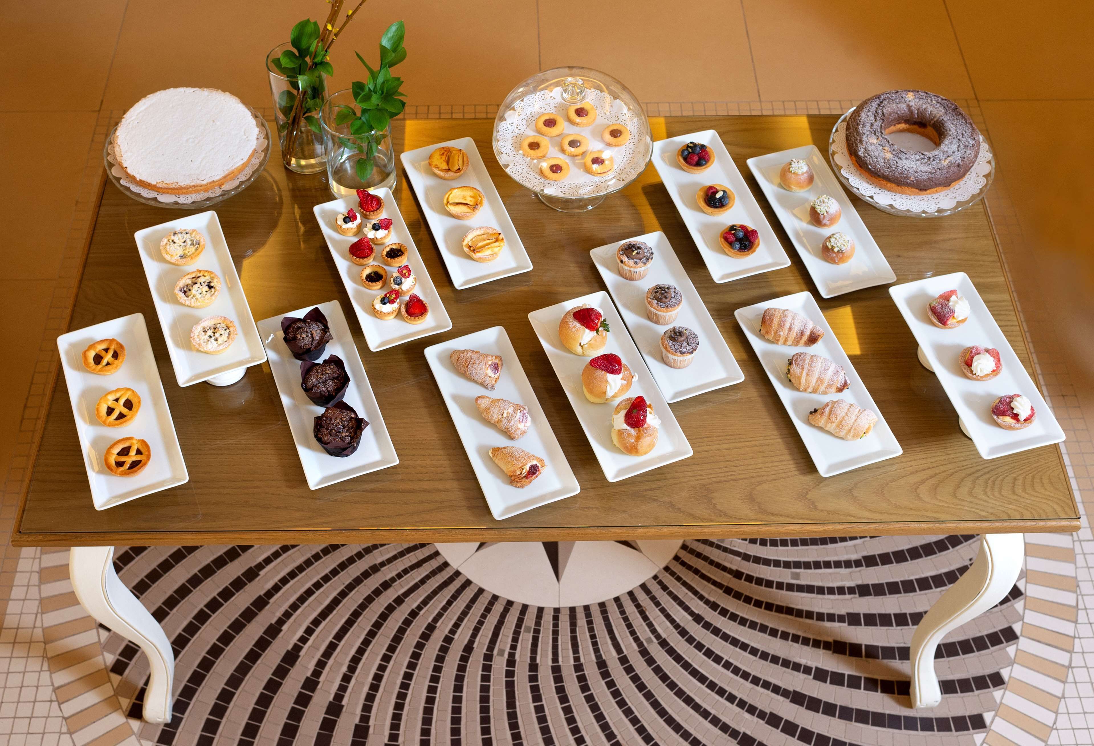 A table with various pastries and desserts arranged on white plates.