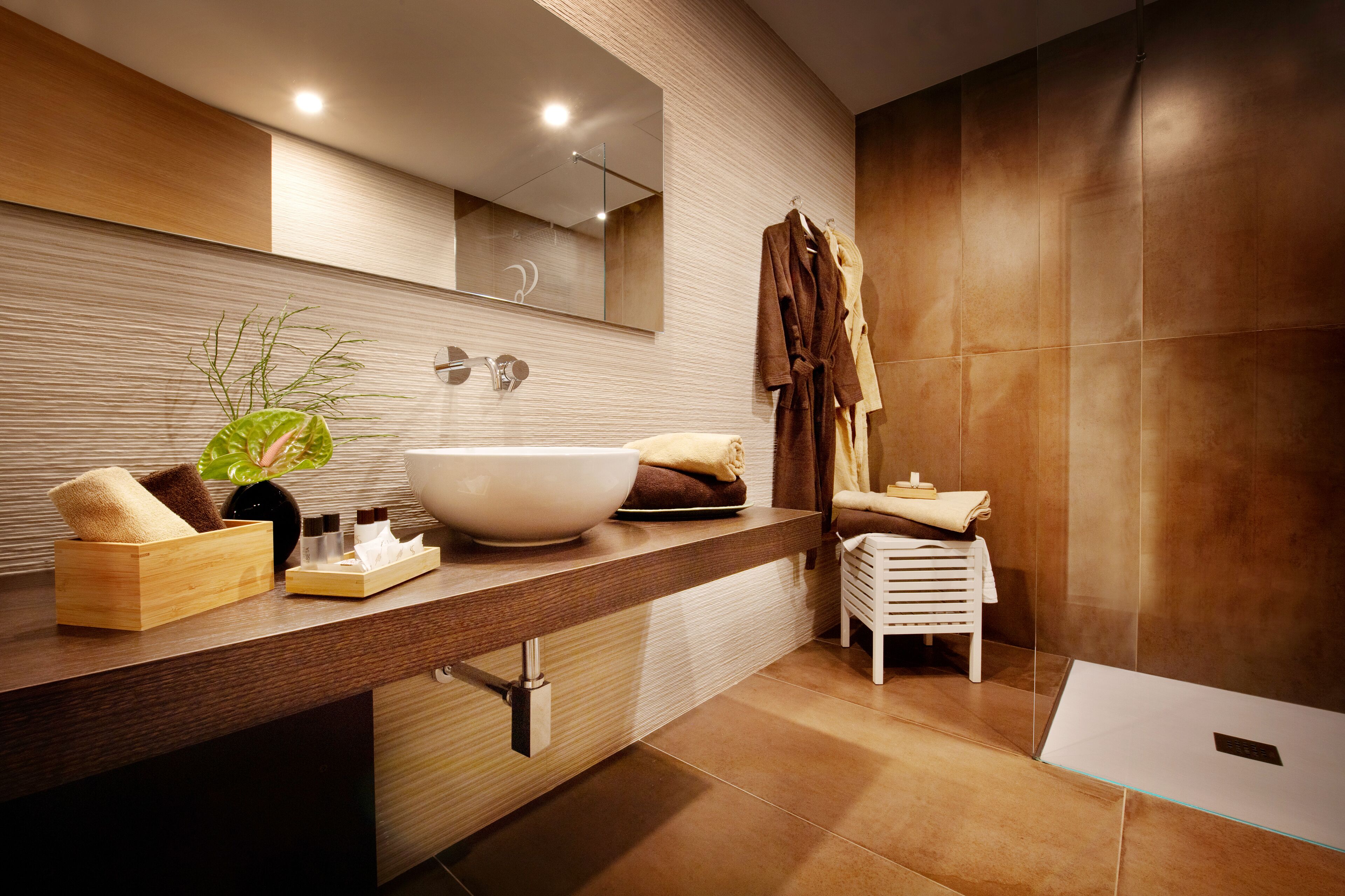 A modern bathroom with a large vessel sink, a mirror, a towel rack, and a small white stool.