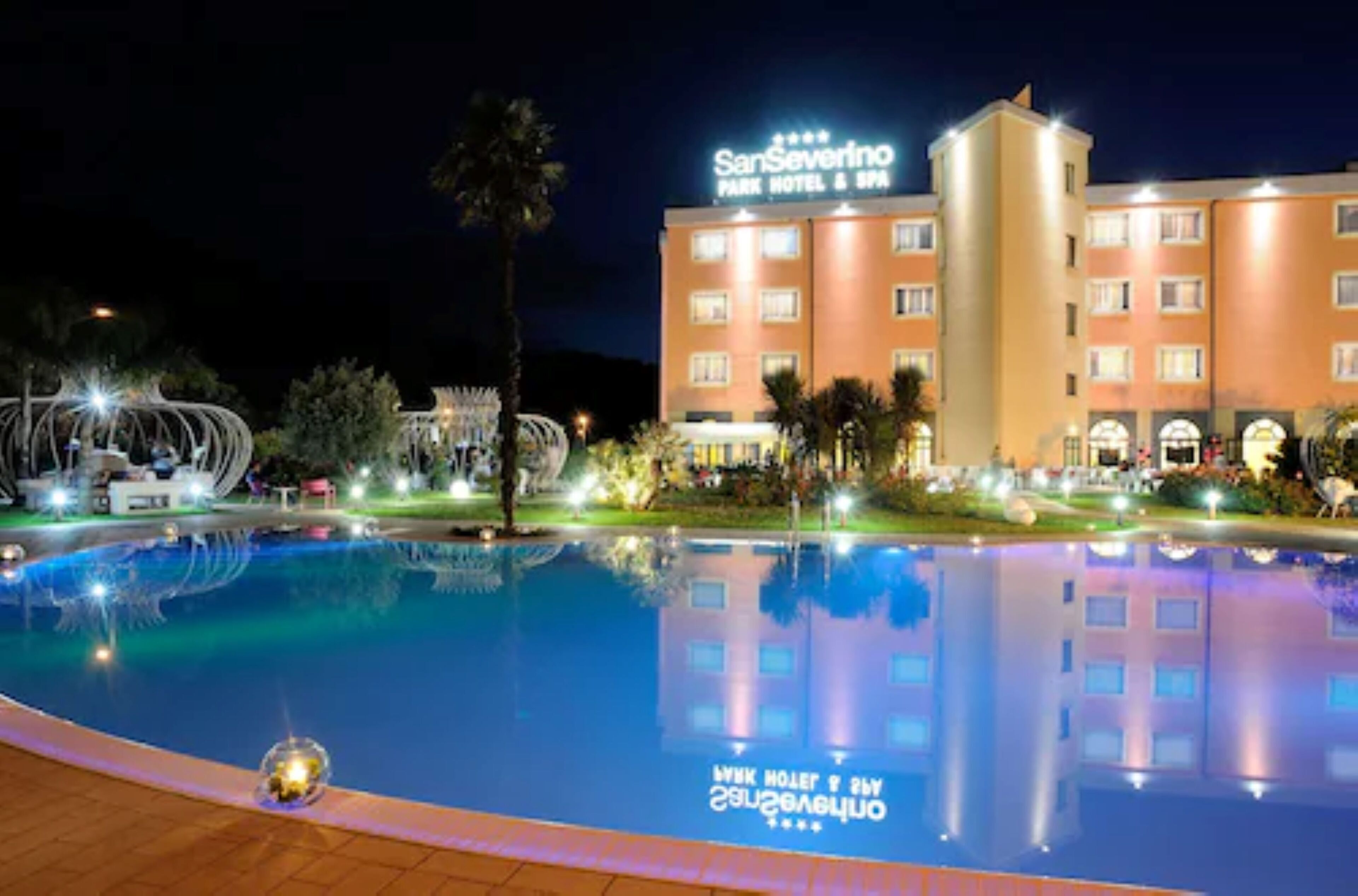 Un hotel con piscina, una facciata ben illuminata e un cartello con la scritta 'SanSeverino Park Hotel & Spa'.
