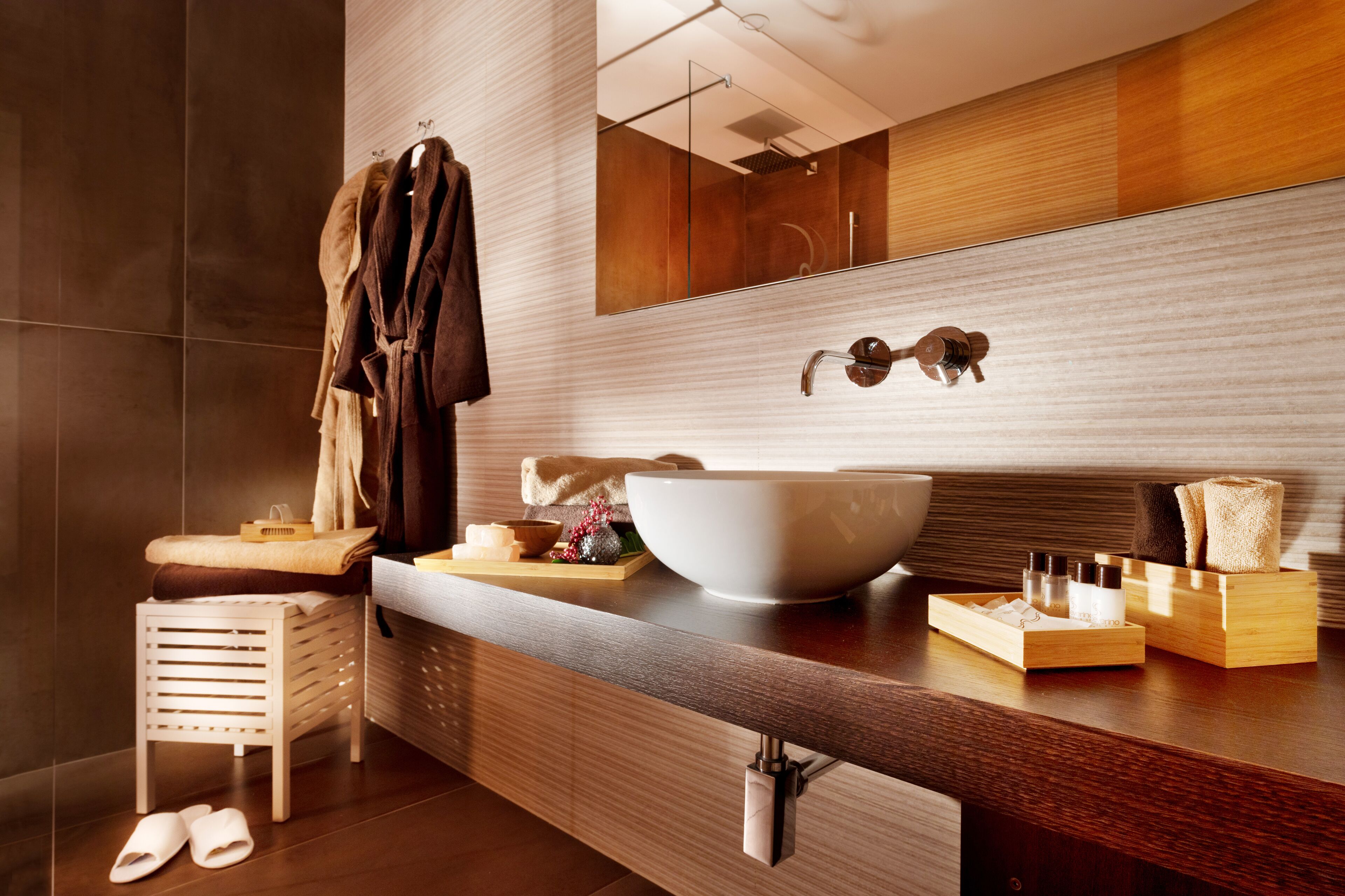 A modern bathroom with a large mirror, a vessel sink, and a wooden vanity.