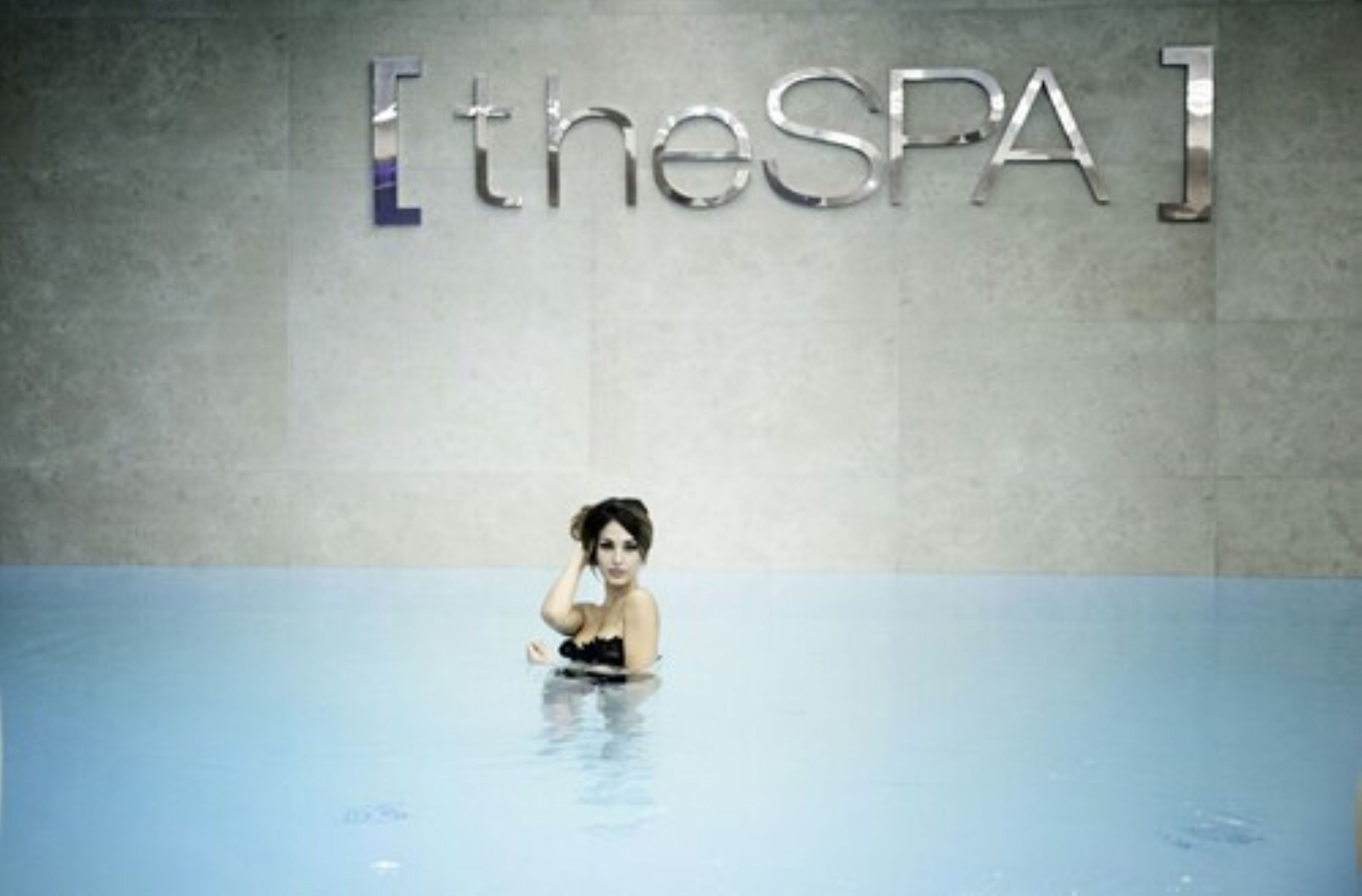 A person in a swimming pool with a sign reading "the SPA" in the background.