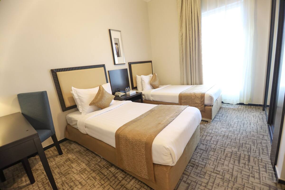 Habitación de hotel con dos camas, un escritorio y una silla.