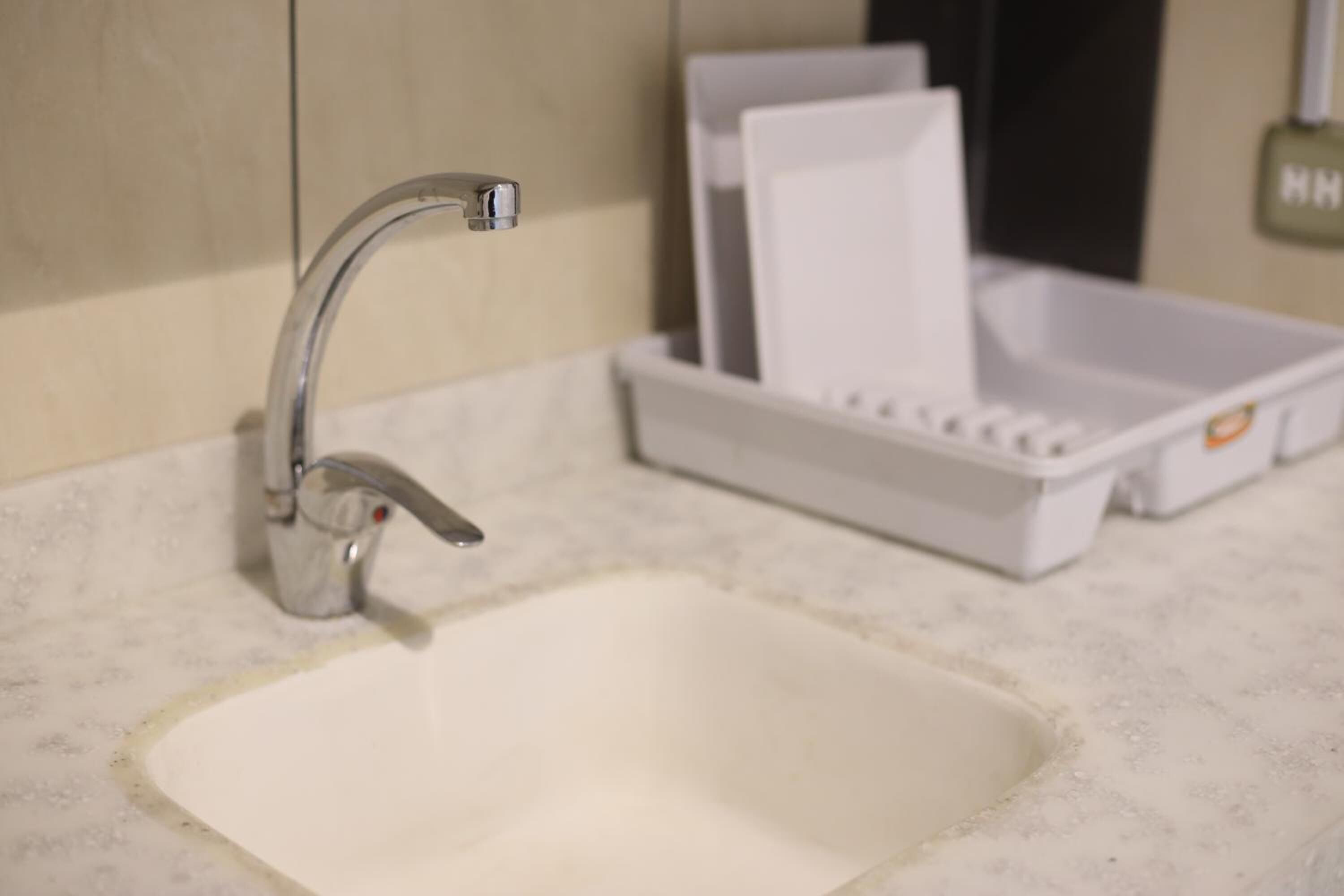 A bathroom sink with a chrome faucet, a white soap dispenser, and a white soap dish.