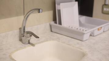 A bathroom sink with a chrome faucet, a white soap dispenser, and a white soap dish.