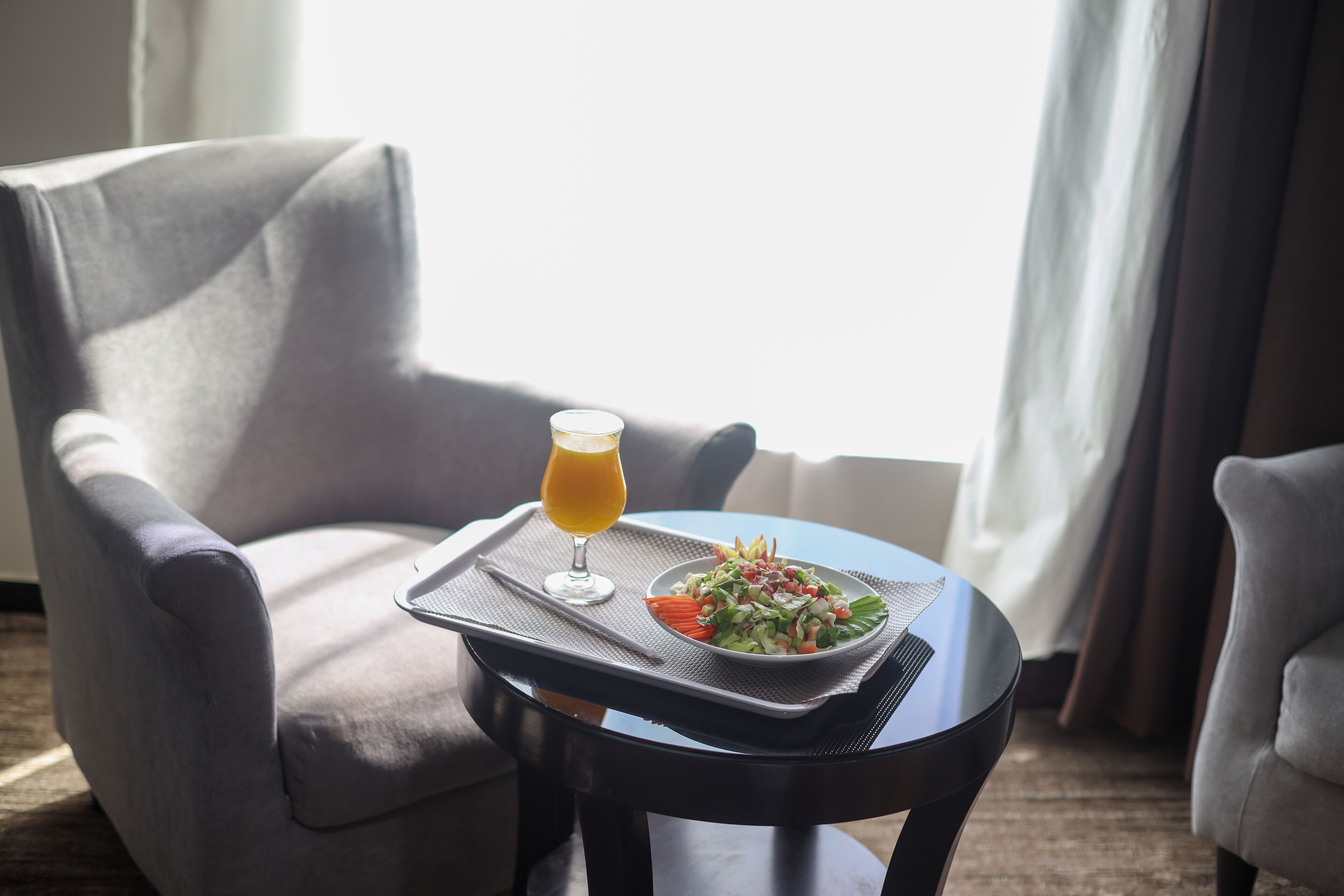 A dining area with a table set for a meal, a glass of orange juice, and a plate of salad.