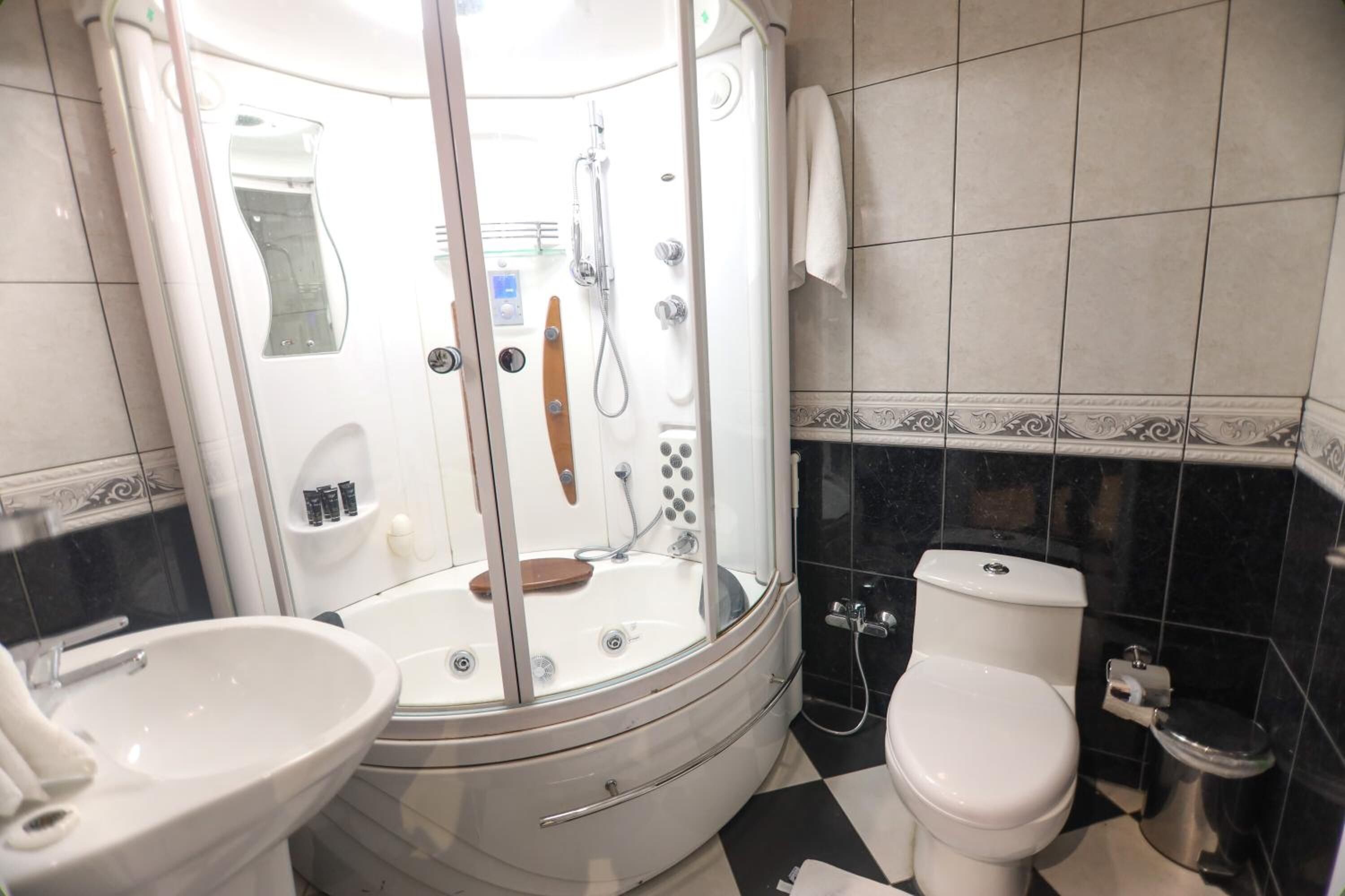 Un baño con cabina de ducha, inodoro y lavamanos.