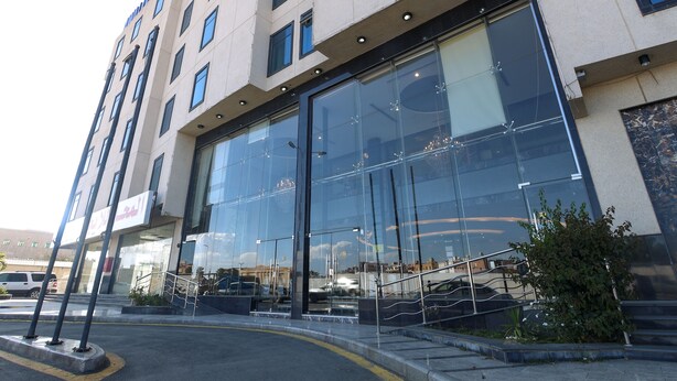 A modern hotel with large glass windows, a visible entrance, and a parking area. - Platinum Park Serviced Apartments (Taif)