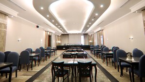 A conference room with a long table and chairs, recessed ceiling lights, and a marble wall. - Platinum Park Serviced Apartments (Taif)