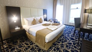 A hotel room with a large bed, a desk, and a chair. - Platinum Park Serviced Apartments (Taif)
