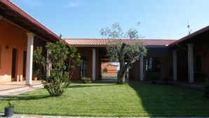 A building with a red roof and columns, a well-maintained lawn, and a clear sky. - CuccuruAio' B&B (Siamaggiore)