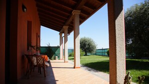 An outdoor patio with a wooden ceiling, a table with chairs, and potted cacti. - CuccuruAio' B&B (Siamaggiore)