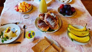 A breakfast table with various dishes including croissants, fruit, and bread. - CuccuruAio' B&B (Siamaggiore)