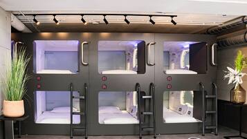 Une chambre sur le thème du train, avec des lits superposés, des portes numérotées et une plante en pot.