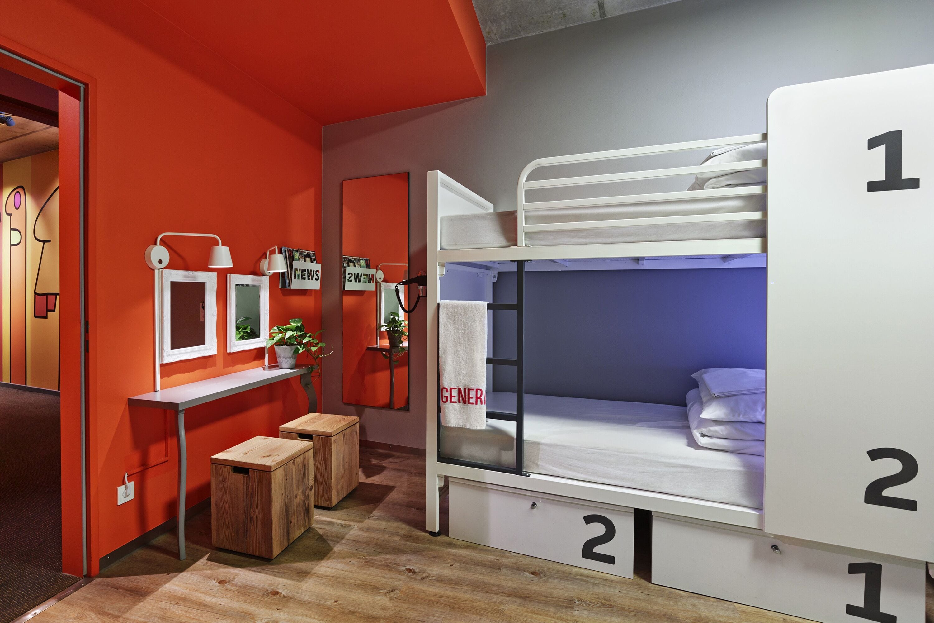 Une chambre avec des lits superposés, un bureau et un petit coin salon.