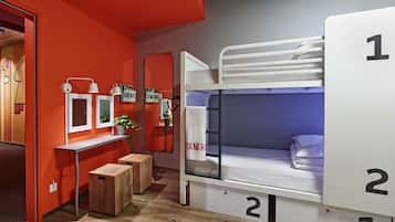 Une chambre avec des lits superposés, un bureau et un petit coin salon.