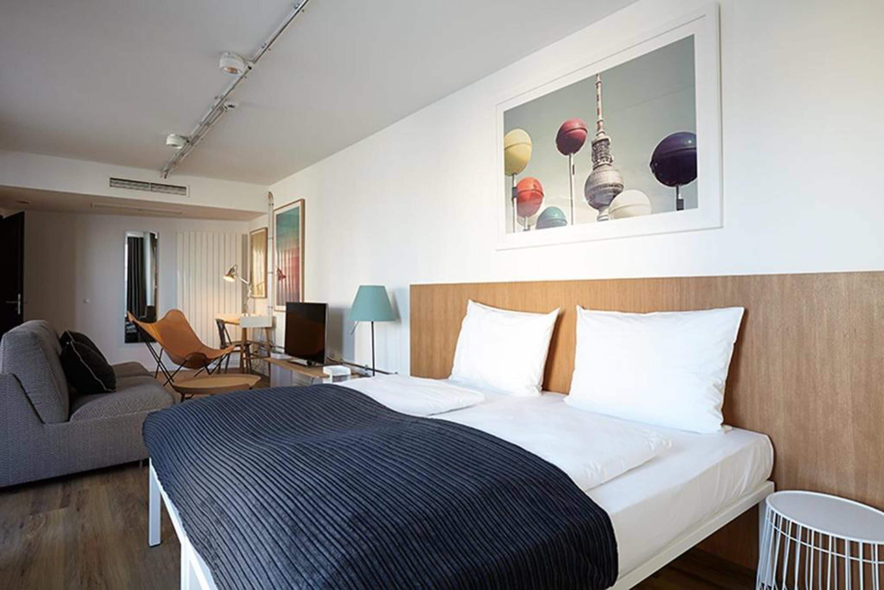 A hotel room with a bed, a desk, a chair, and a television.