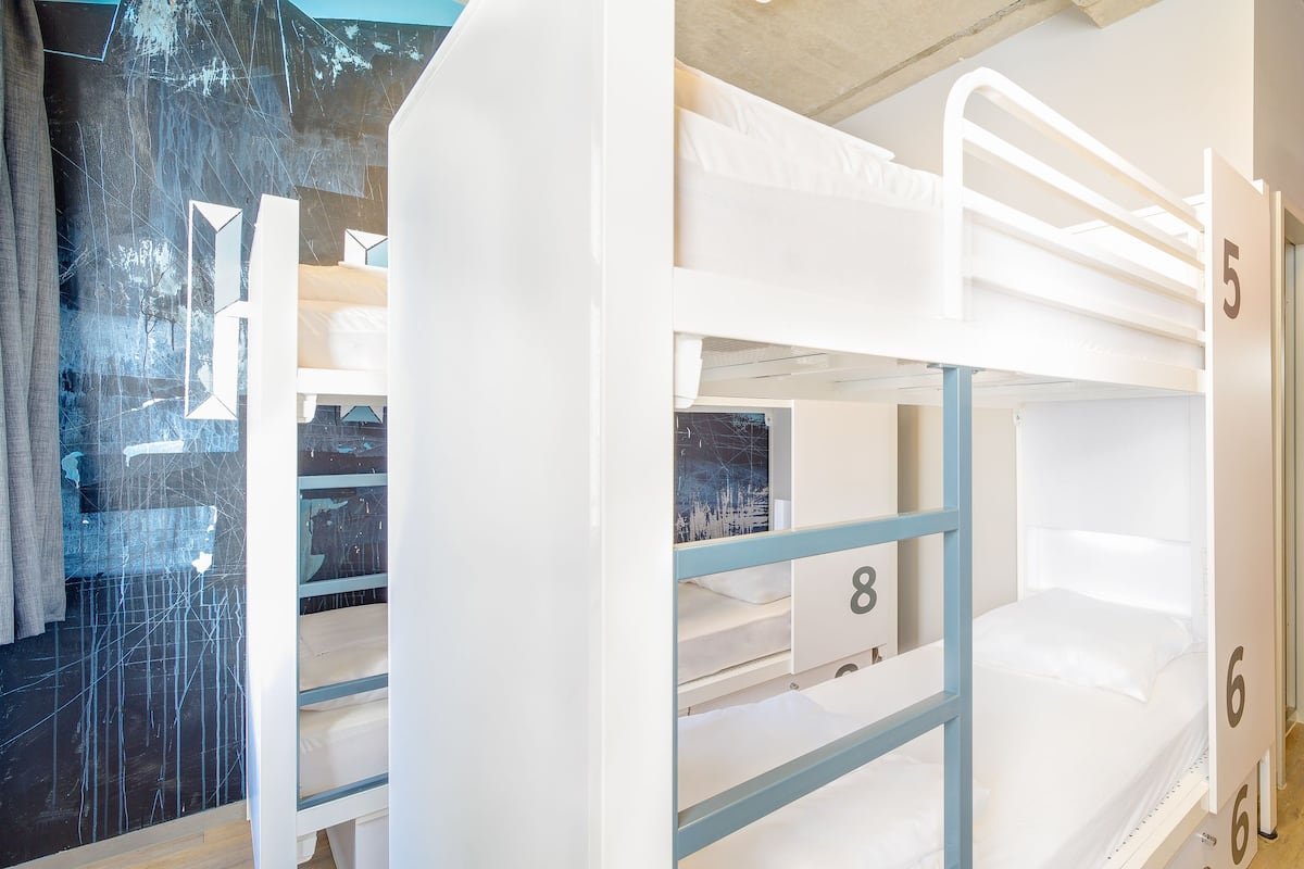 A corridor with bunk beds numbered 5, 6, and 8, leading to a room with a red wall.