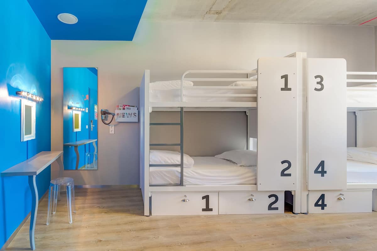 A bunk bed room with numbered storage drawers, a desk, and a stool.