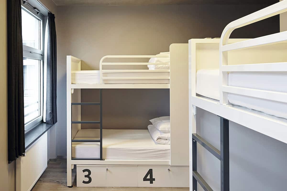 A bunk bed room with a window, a radiator, and a door.