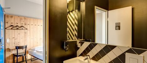 A modern bathroom with a black and white checkered floor, a white sink, and a mirror with a black and white striped towel hanging on it.