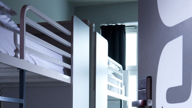 Dormitorio con literas, una puerta y un radiador.