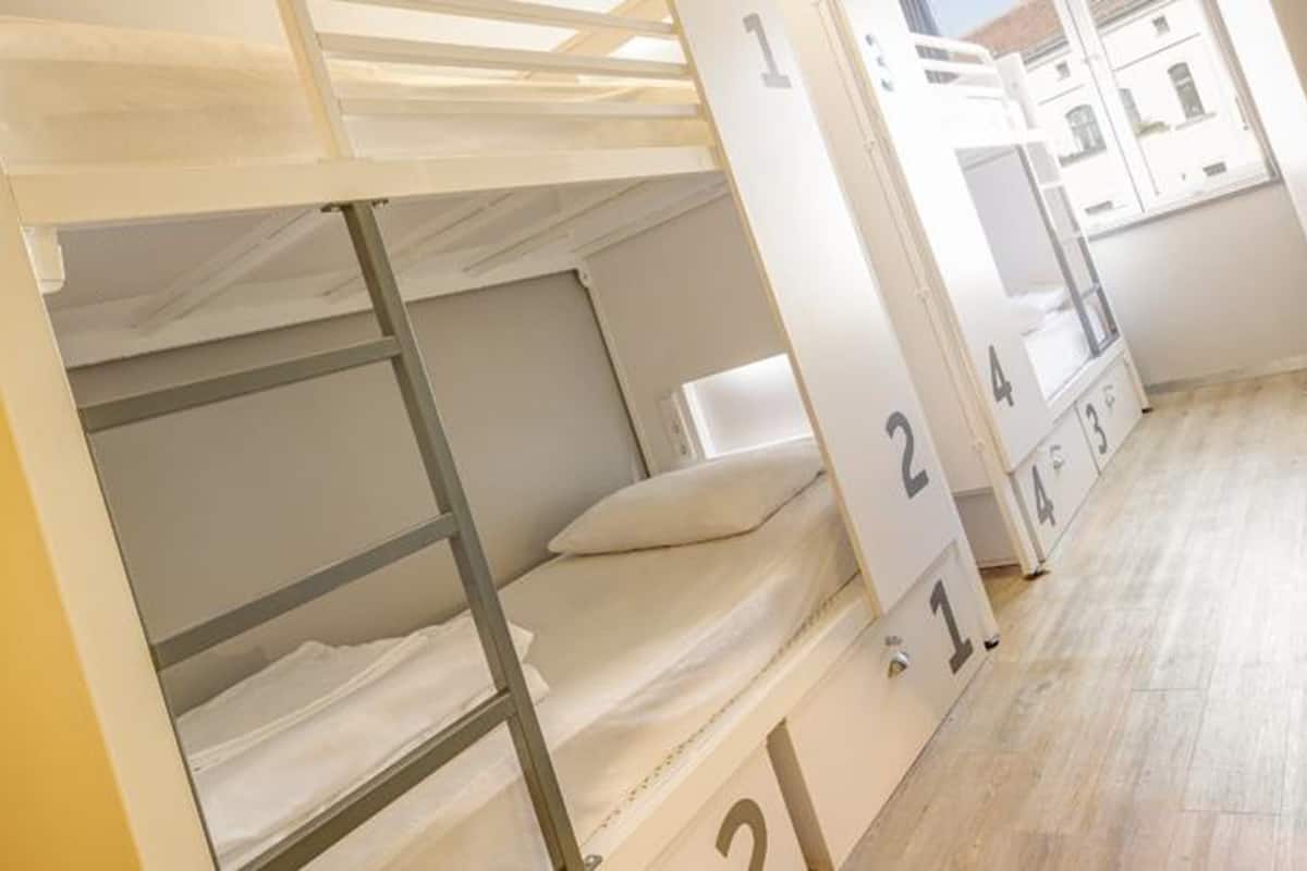 A bunk bed room with a wooden floor and a view of a building outside.