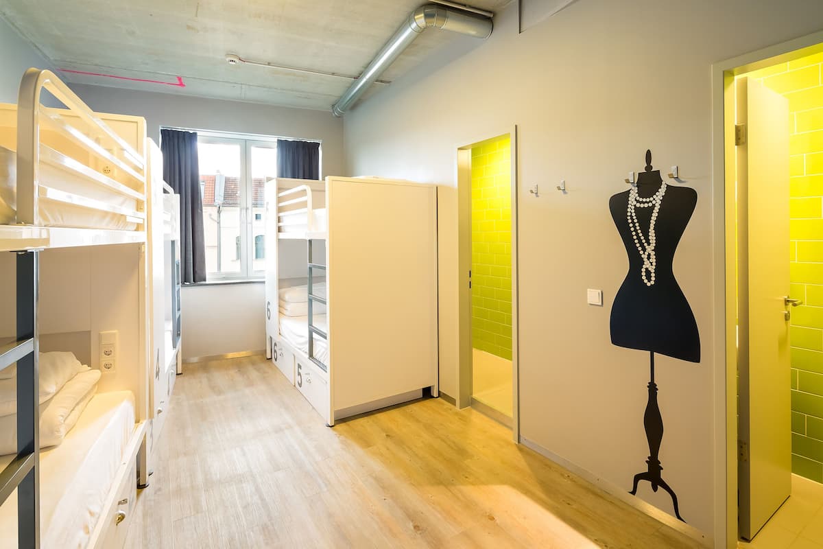 A corridor with bunk beds, a mannequin with jewelry, and a bright yellow door.