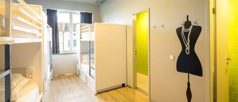 A corridor with bunk beds, a mannequin with jewelry, and a bright yellow door.