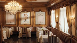 A formal dining room with chandeliers, framed artwork, and a long bench along the wall. - Hotel Colbricon  (Primiero San Martino di Castrozza)