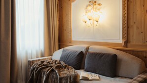A cozy room with a bed, a blanket, and a wall-mounted light fixture. - Hotel Colbricon  (Primiero San Martino di Castrozza)