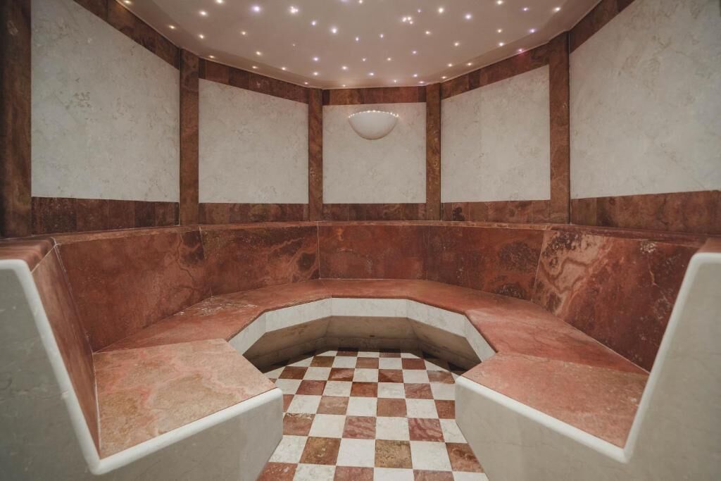 Une salle de spa dotée d’un sol à carreaux, d’un espace salon central et d’un plafond avec des luminaires encastrés.