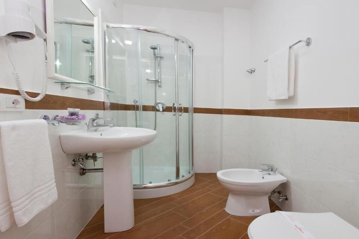 Un baño con cabina de ducha de vidrio, lavamanos, inodoro y bidé.