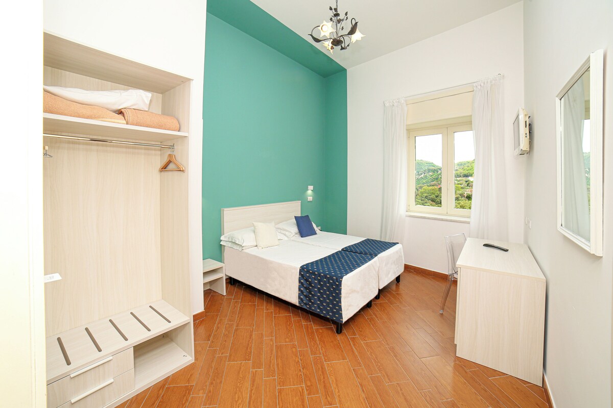 Une chambre à coucher avec un lit, un bureau, une armoire et une fenêtre donnant sur un beau paysage.