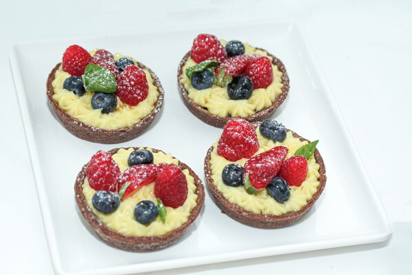 Vier gebakjes met fruit op een wit bord.