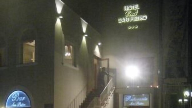 Ein Hotel Eingang mit einer Treppe zum Empfangsbereich, einem Bar Schild und mehreren beleuchteten Kerzen auf dem Boden.