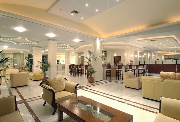 A spacious lobby with multiple seating areas, a reception desk, and a dining area. - Selini Suites (Platanias)