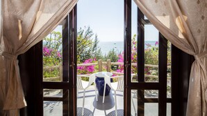 An open door with a view of a patio area, a table with chairs, and a vase.