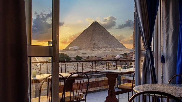 A balcony with a view of a pyramid, a table, and chairs. - Pyramids View inn Bed & Breakfast (Giza)
