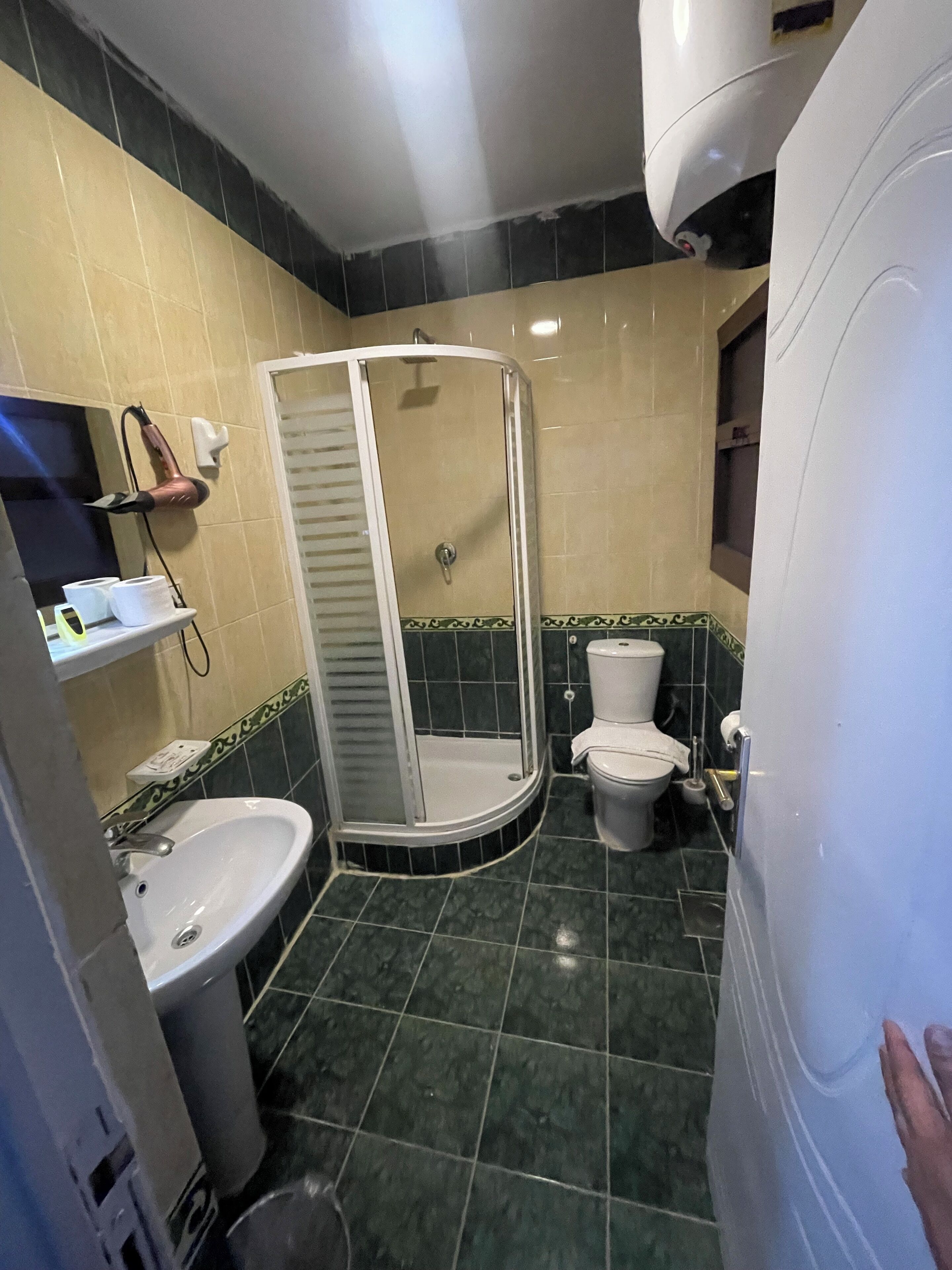 A bathroom with a shower, sink, toilet, and a mirror.
