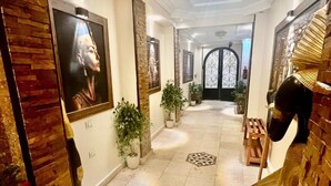 A hallway with a wooden accent wall, potted plants, and framed artwork. - Pyramids View inn Bed & Breakfast (Giza)